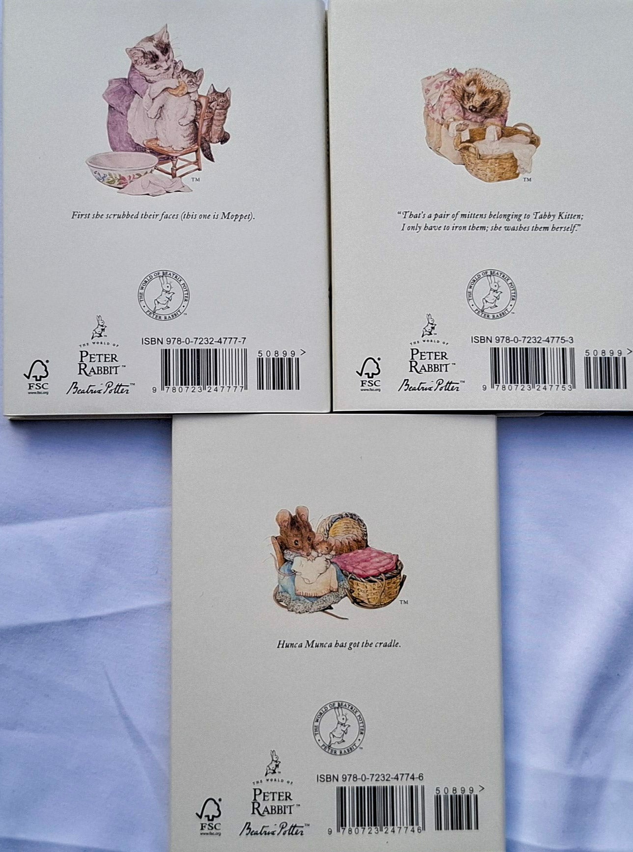 Back covers of books featuring illustrations of characters from 'Peter Rabbit' series on a light blue fabric background.