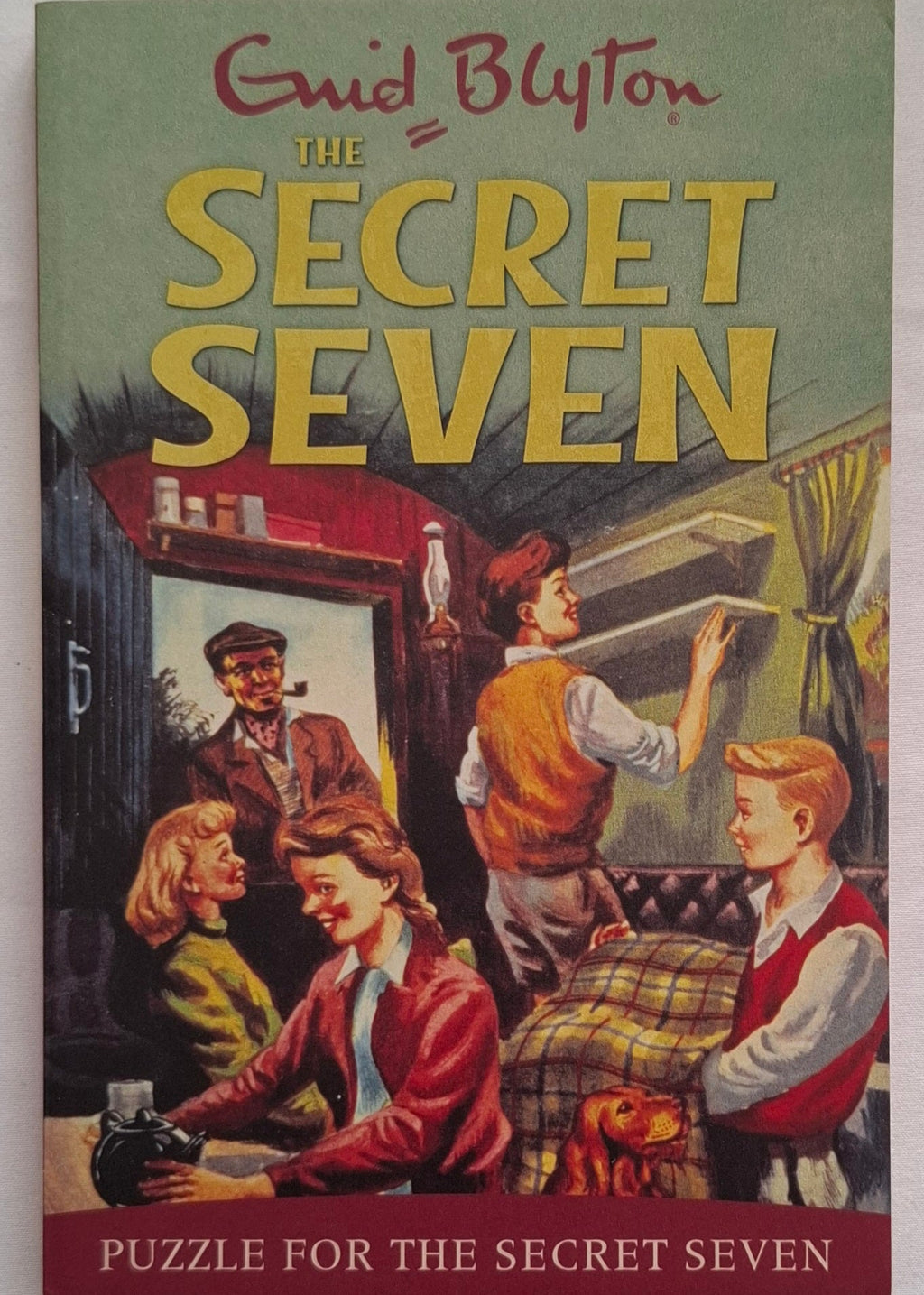 Book cover of 'The Secret Seven' by Enid Blyton featuring children around a table.