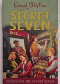 Book cover of 'The Secret Seven' by Enid Blyton featuring children around a table.